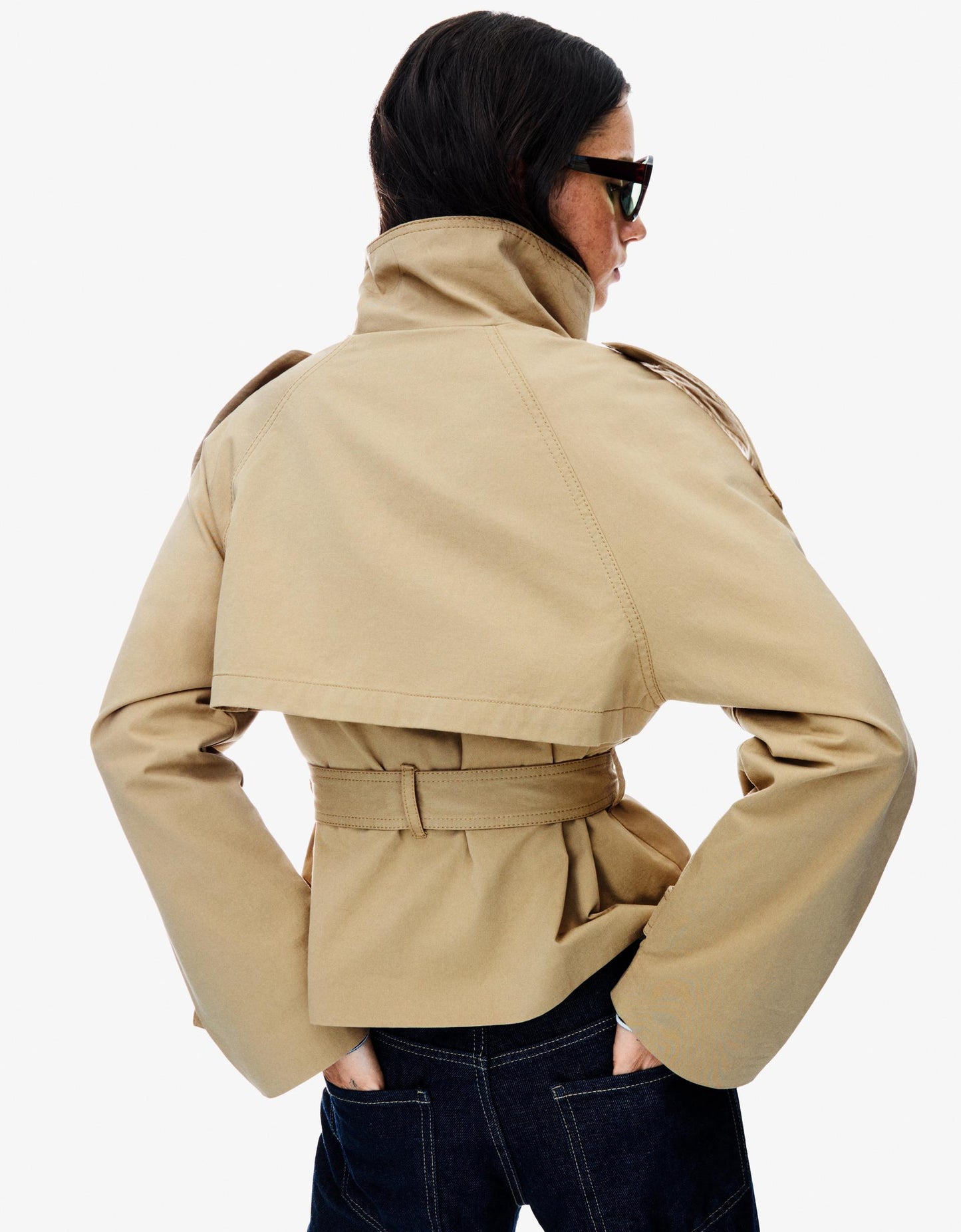 frau trägt beige cropped trenchcoat mit epauletten und doppelknöpfen