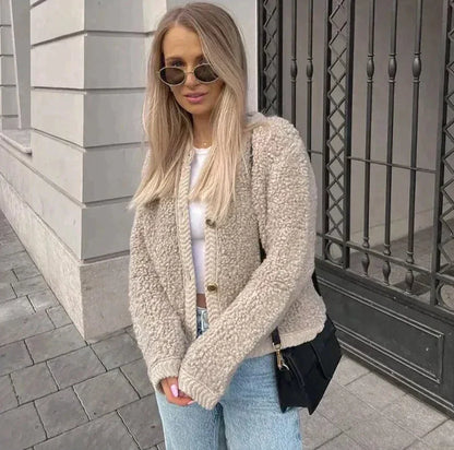 Frau trägt beigefarbenes Teddy Cardigan mit Knöpfen und schwarze Jeans