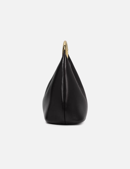 nahaufnahme ivorene tasche mit großem goldenem ringhenkel